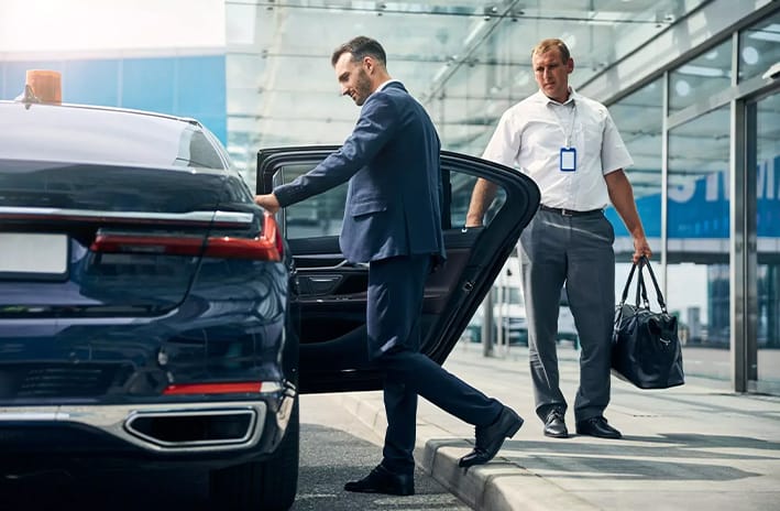 Chauffeur WiTaxi aidant un client avec ses bagages à l’aéroport de Bâle-Mulhouse